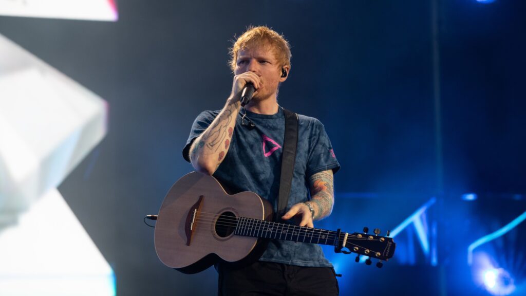 Ed Sheeran performing on stage at Melbourne's MCG in 2023, previewing the 2026 Loop Tour at Marvel Stadium.
